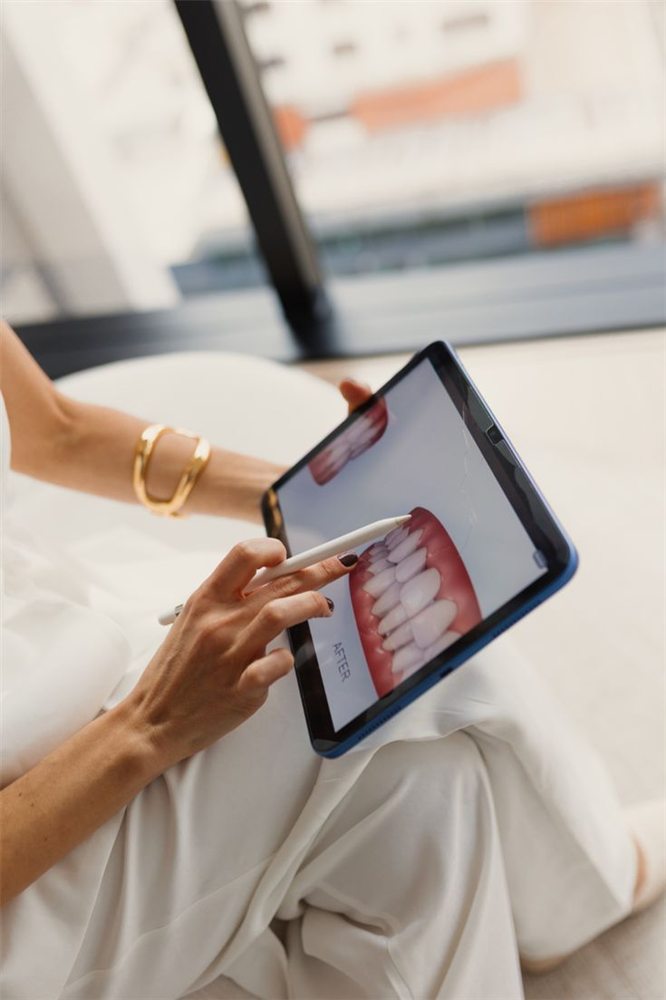 Profesional mostrando en una tablet el antes y el después de un tratamiento dental